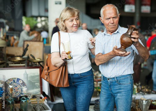 Fotografia Smiling mature spouses buying retro handicrafts on flea market