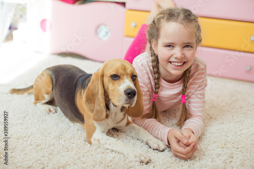 Happy child with a dog. Portrait of a girl with a pet. Beagle licks a teenager. High quality photo.