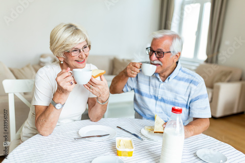 Senior couple having breakfast and drinking coffee. Elderly couple having their meal at home. An old man and woman sitting at the table, relaxing. photo