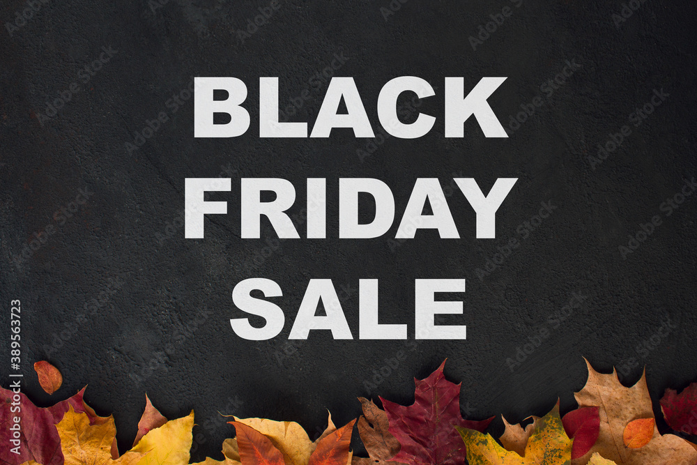 Fototapeta premium Black friday sale banner with autumn leaves on dark concrete background.