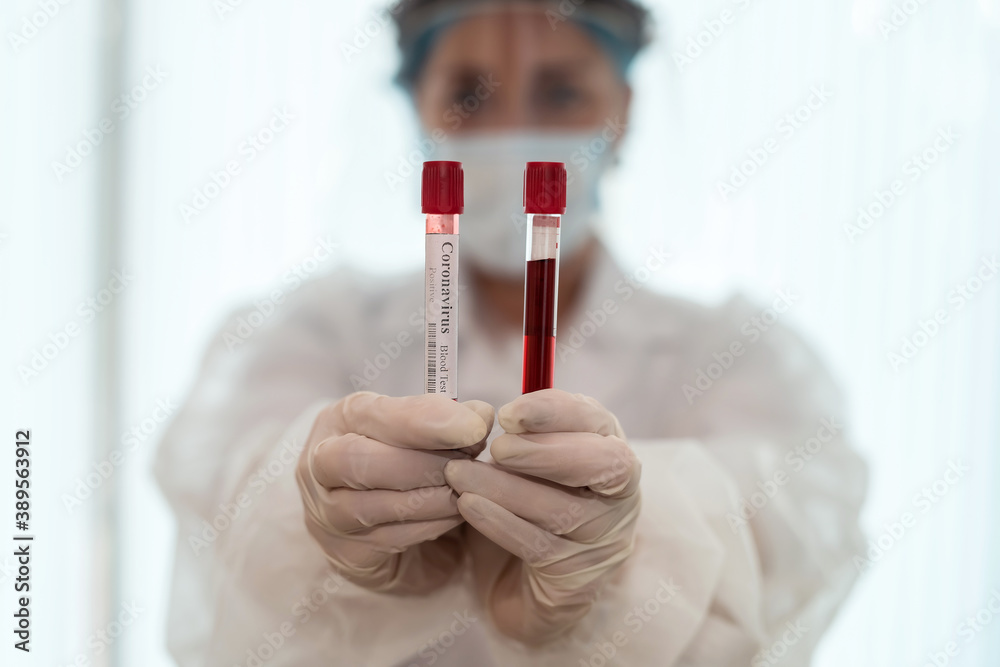 doctor wearing personal protective equipment looking at a test tube labeled coronavirus test doctor wearing personal protective equipment looking at a test tube labeled coronavirus test