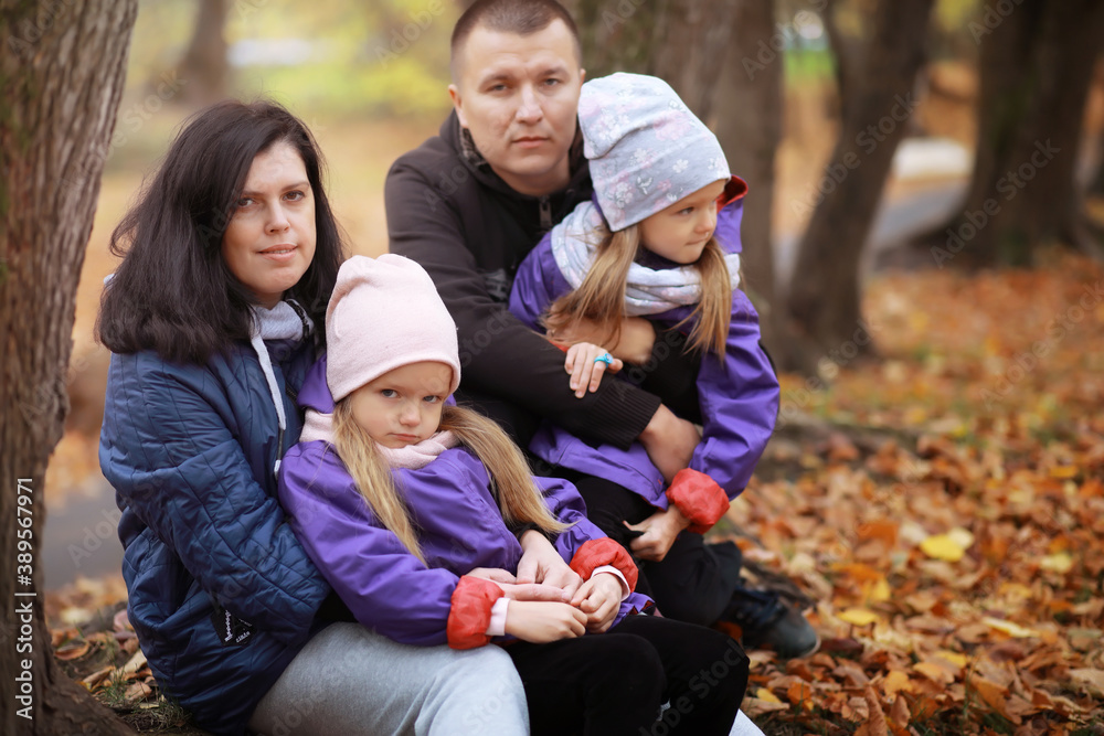 Young family on a walk in the autumn park on a sunny day. Happiness to be together.