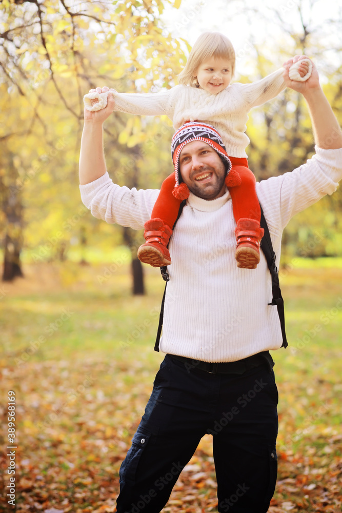 Obraz premium Young family on a walk in the autumn park on a sunny day. Happiness to be together.
