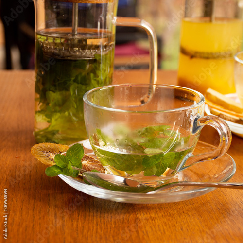 Transparent cup for tea with mint leaves and dried fruits on a wooden table. cafe concept