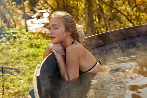 good-looking slim female having rest inside of hot bath in the nature, countryside. in jacuzzi. sit with eyes closed