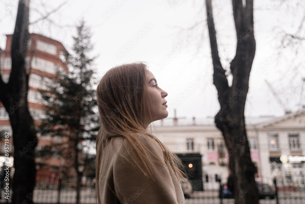 profile of a young girl in a coat against the background of an urban environment