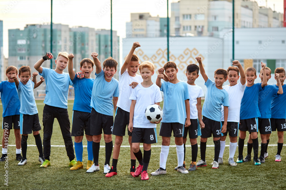 portrait of confident team of young football players posing at camera, athletic boys in uniform going to play football or soccer. in stadium