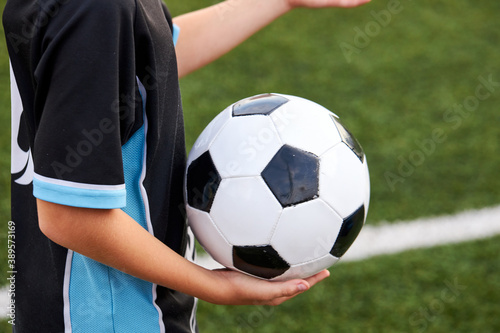 close-up photo of ball in hands of football player, cropped child boy in uniform going to play © Roman