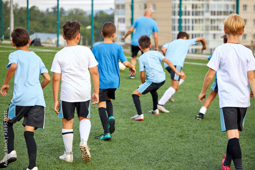 training and football match between youth soccer teams in stadium, boys have hard competition, running and kicking soccer ball