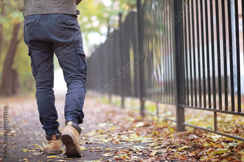 Autumn concept. Pedestrian feet on the road. Autumn leaves on the footpath. © alexkich
