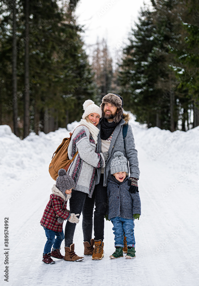 Father and mother with two small children in winter nature, standing in the snow.