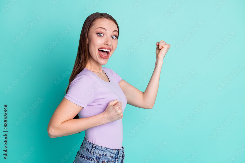 Side profile photo of girl smiling gesturing like winner isolated on bright teal color background with empty space Side profile photo of girl smiling gesturing like winner isolated on bright teal color background with empty space