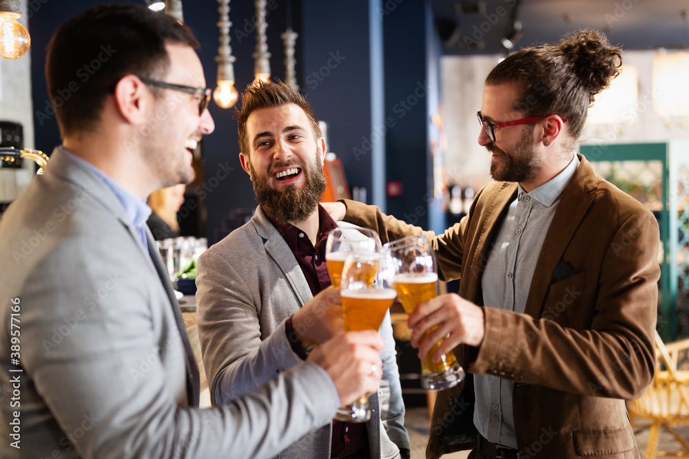 Young businessmen are drinking beer, talking and smiling while resting at the pub