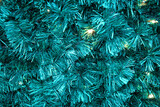 Background of blue artificial Christmas tree with garlands. Tinsel decorations for new year and christmas, copy space