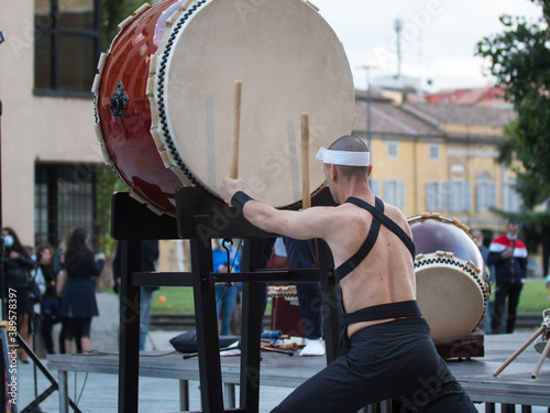 Man with Headband Playing Vertical Drum of Japanese Musical Tradition during a Public Outdoor Event photo