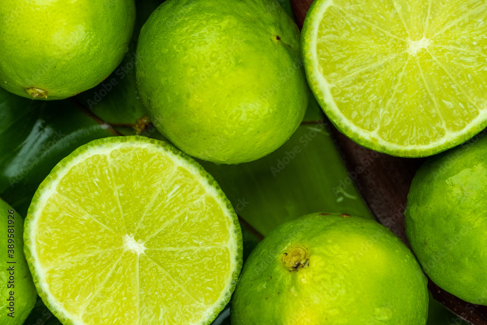 Close up pile of half and whole fresh lime juicy on green banana leaves with clearly water drop on surface Close up pile of half and whole fresh lime juicy on green banana leaves with clearly water drop on surface