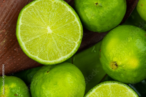 Close up pile of half and whole fresh lime juicy on green banana leaves with clearly water drop on surface