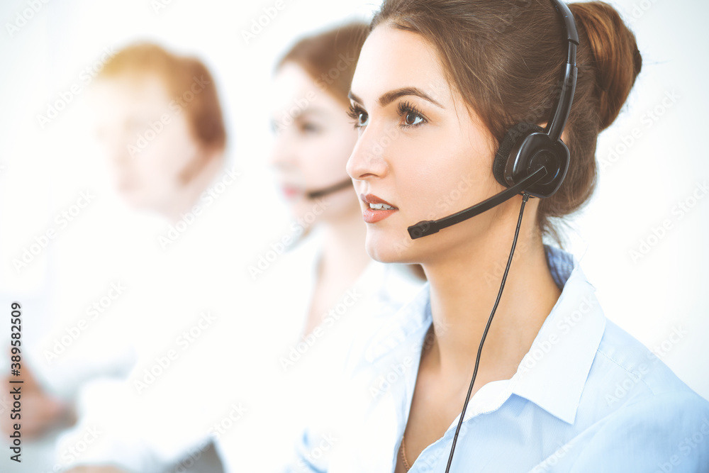 Call center operators. Focus on beautiful business woman using headset Call center operators. Focus on beautiful business woman using headset