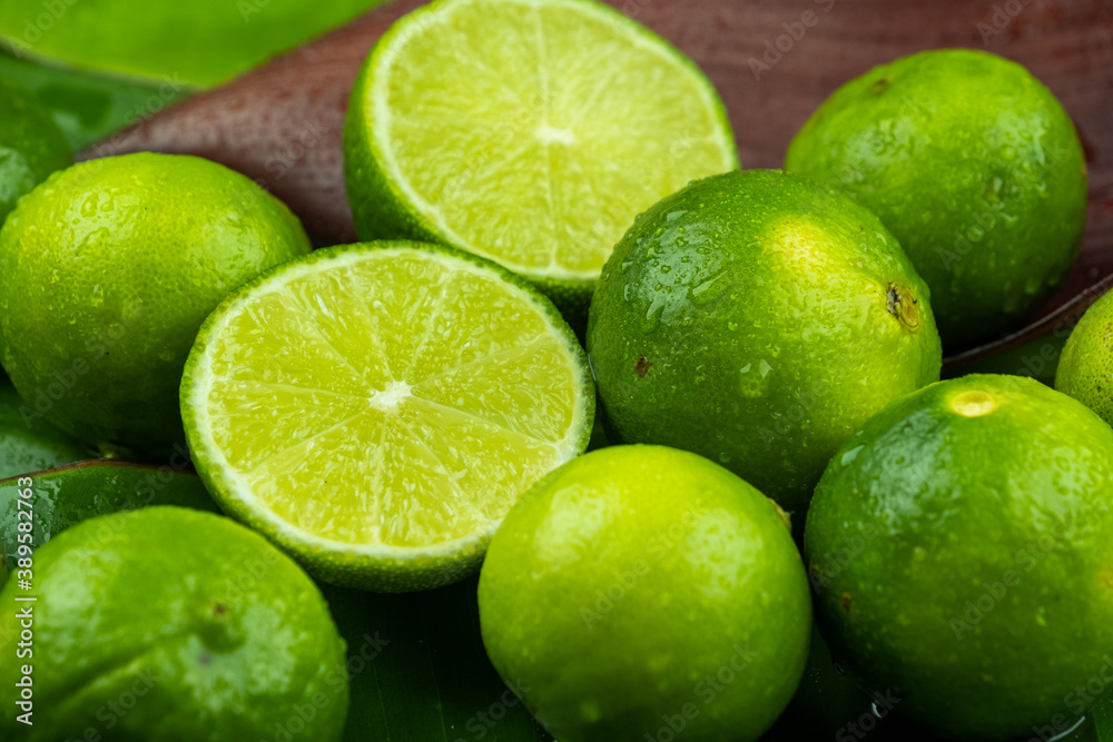 Close up pile of half and whole fresh lime juicy on green banana leaves with clearly water drop on surface Close up pile of half and whole fresh lime juicy on green banana leaves with clearly water drop on surface