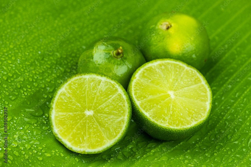 Close up pile of half and whole fresh lime juicy on green banana leaves with clearly water drop on surface Close up pile of half and whole fresh lime juicy on green banana leaves with clearly water drop on surface