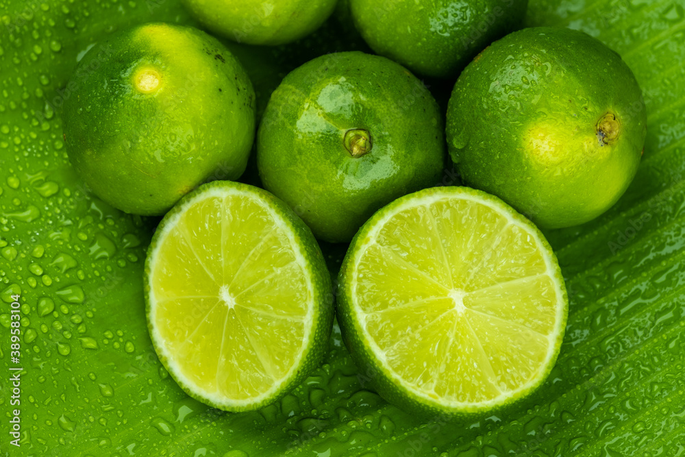 Close up pile of half and whole fresh lime juicy on green banana leaves with clearly water drop on surface Close up pile of half and whole fresh lime juicy on green banana leaves with clearly water drop on surface