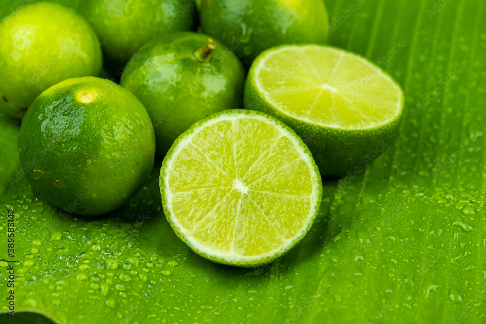 Close up pile of half and whole fresh lime juicy on green banana leaves with clearly water drop on surface Close up pile of half and whole fresh lime juicy on green banana leaves with clearly water drop on surface