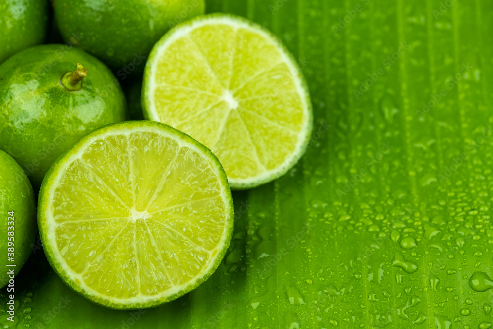 Close up pile of half and whole fresh lime juicy on green banana leaves with clearly water drop on surface Close up pile of half and whole fresh lime juicy on green banana leaves with clearly water drop on surface