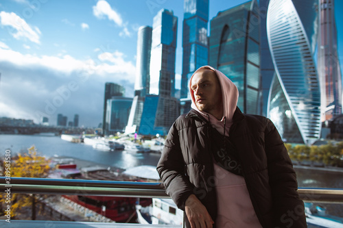 Photography Handsome casual man in black jacket and pink hoody standing on a skyscraper view
