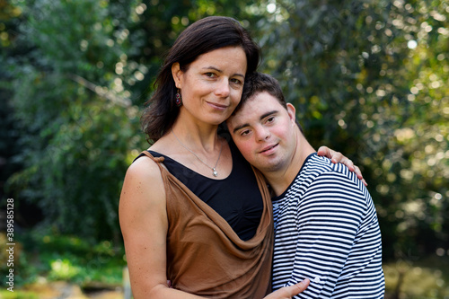 Portrait of down syndrome adult man with mother standing outdoors in garden. photo