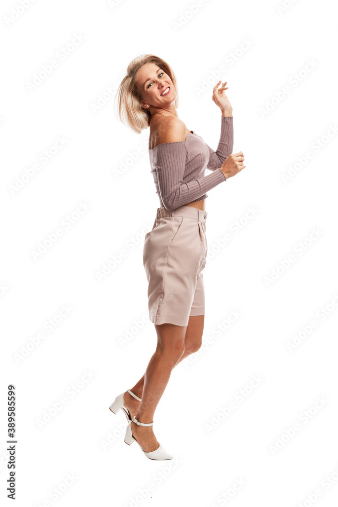 Smiling young blonde woman in pink suit jumping. Isolated on white background. Vertical.