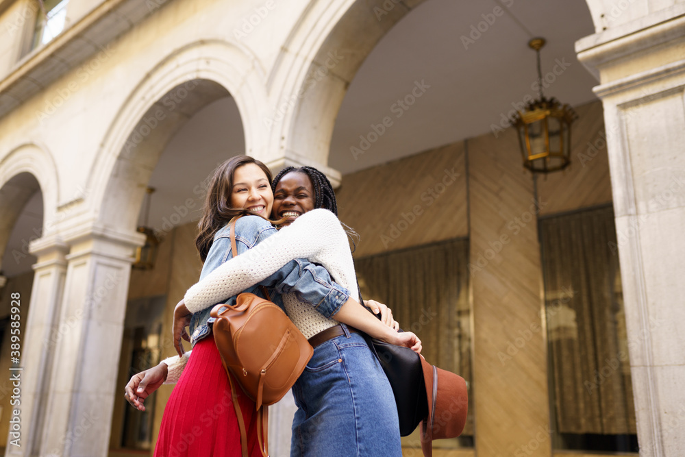 Two friends happy to see each other on the street hugging.