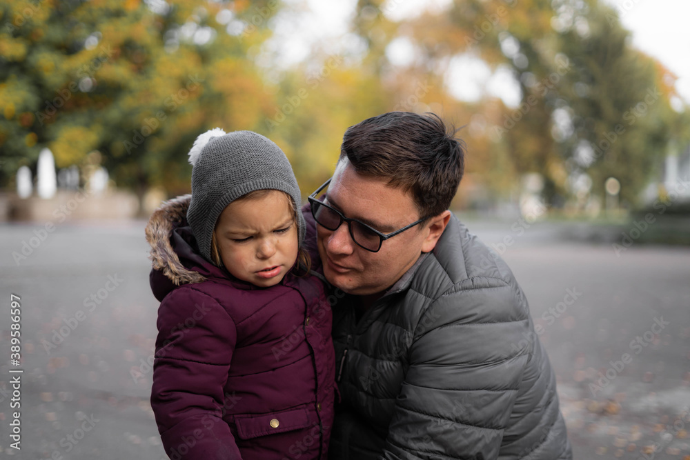 Fototapeta premium Father comforting toddler child, parent support. Autumn, yellow leaves. Outdoors kids activity