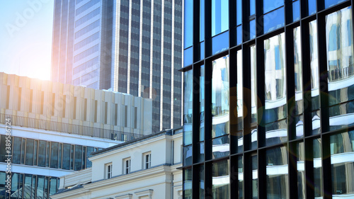 Blue curtain wall made of toned glass and steel constructions under blue sky. A fragment of a building. Glass facades on a bright sunny day with sunbeams in the blue sky.