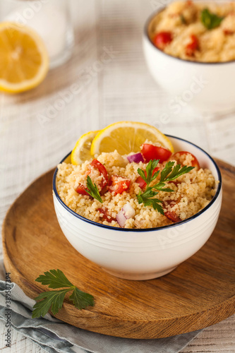 Tabouleh is an Arabic vegetarian salad made with couscous, tomatoes, parsley. Healthy lunch on a wooden background.