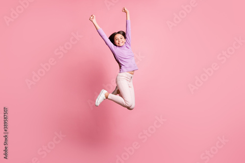 Full length photo of little kid girl jump raise hands wear violet sweater isolated over pastel color background