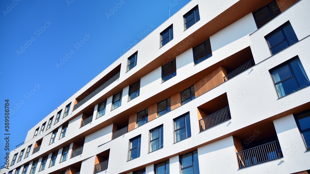 Obraz premium Modern and new apartment building. Multistoried modern, new and stylish living block of flats. Facades on a bright sunny day with sunbeams in the blue sky.