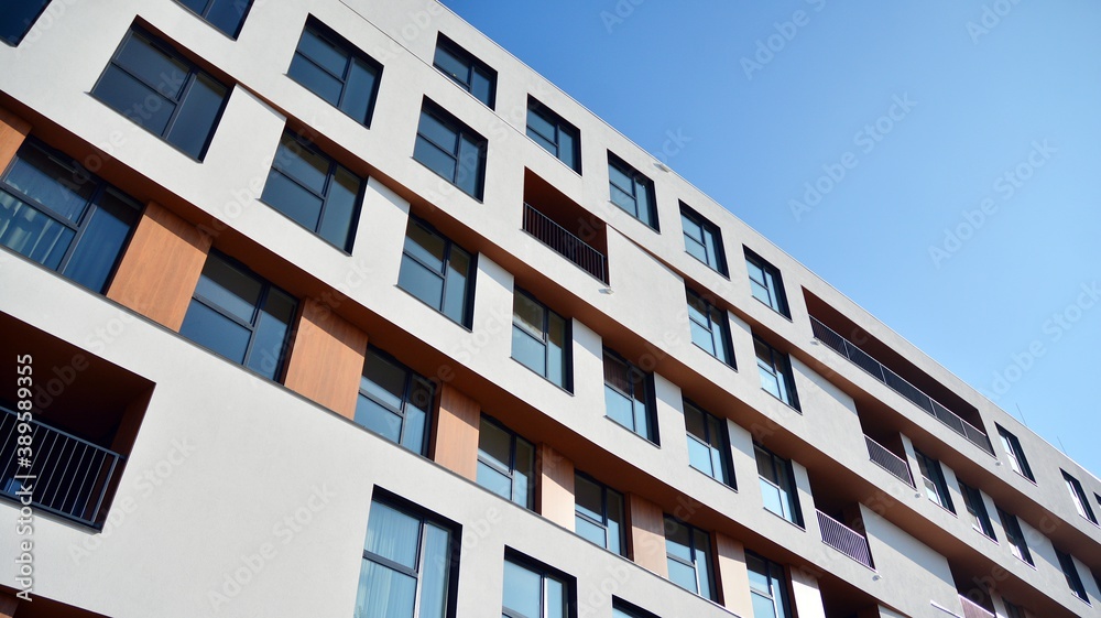 Modern and new apartment building. Multistoried modern, new and stylish living block of flats. Facades on a bright sunny day with sunbeams in the blue sky.