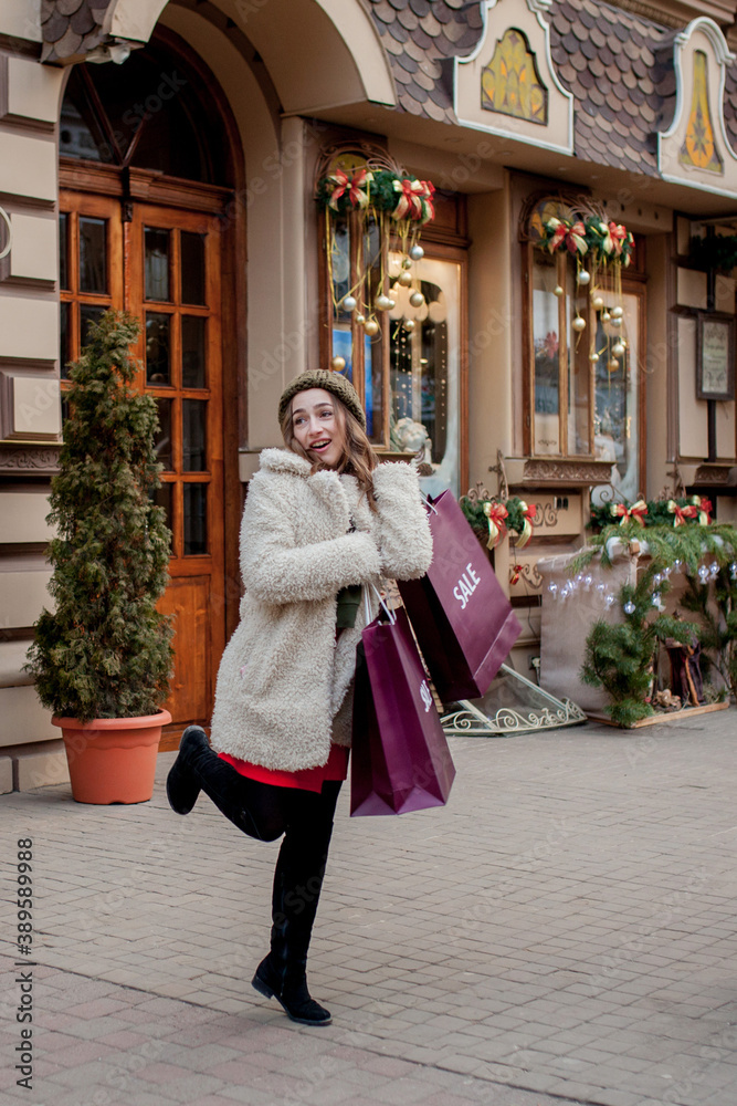 Happy woman holds paperbags with symbol of sale in the stores with sales at Christmas, around the city. Concept of shopping, holidays, happiness, Christmas Sales.