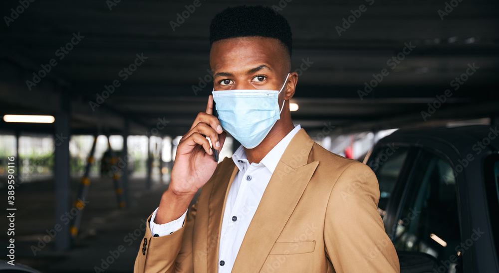 Businessman Wearing Mask Using Mobile Phone In Airport Car Park During Health Pandemic Businessman Wearing Mask Using Mobile Phone In Airport Car Park During Health Pandemic