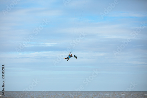 Man in a black wetsuit floats in the air while kitesurfing on the North Sea