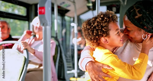 African-american mother kissing and rubbing noses with son inside bus
