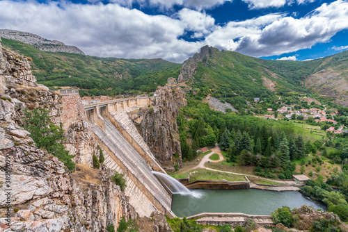 фотографія Profile view of dam spillway with zigzag steps and village