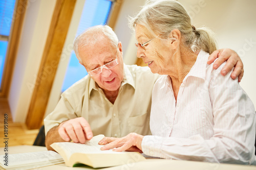 Senior couple with book reading and reading aloud