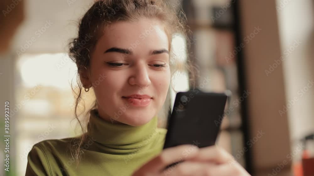 Woman using mobile phone sitting in a cafe texting sms or browsing website