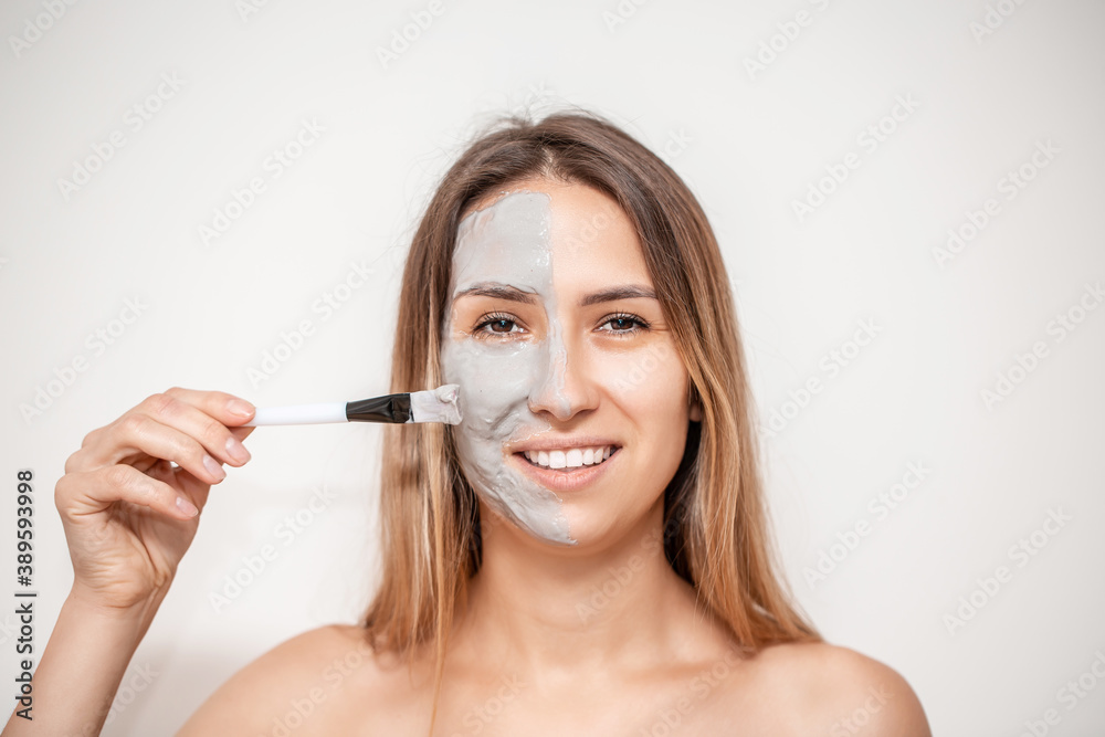 The cosmetologist for procedure of cleansing and moisturizing the skin, applying a Alginic mask to the face of a young woman. Beauty facial mask, skin care and treatment concept