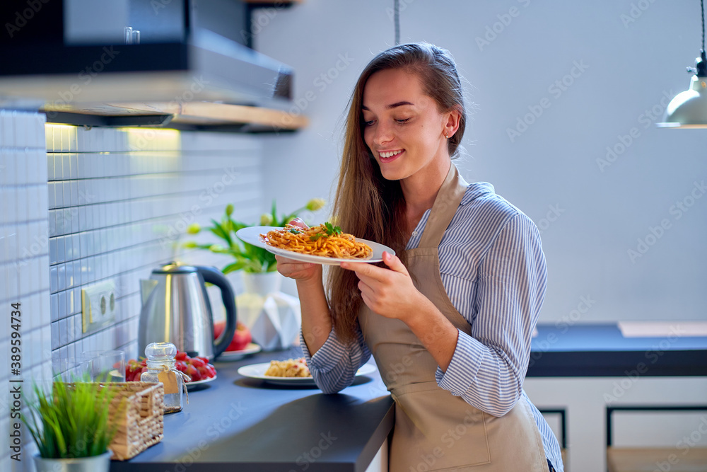 Portrait of smiling happy joyful cute cooking woman chef wearing apron holding a pasta plate for dinner Portrait of smiling happy joyful cute cooking woman chef wearing apron holding a pasta plate for dinner