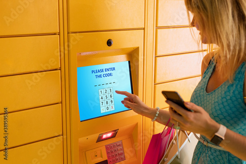 Fotografia, Obraz Woman entering code to receive parcel in post locker