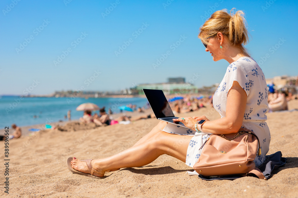 Woman working with laptop on the beach instead of the office