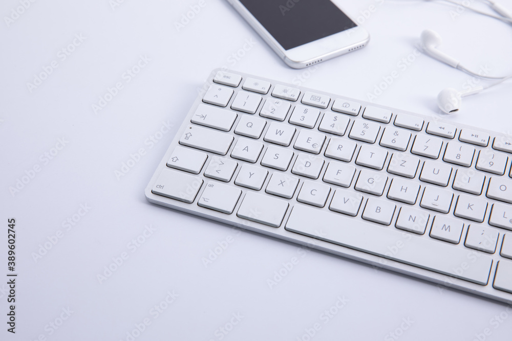 new modern keyboard with smartphone and earphones isolated on white background, close view . High quality photo new modern keyboard with smartphone and earphones isolated on white background, close view . High quality photo