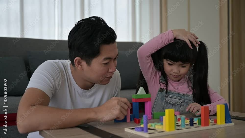 Happy asian family people father playing wooden block on table with daughter together at home living room Happy asian family people father playing wooden block on table with daughter together at home living room